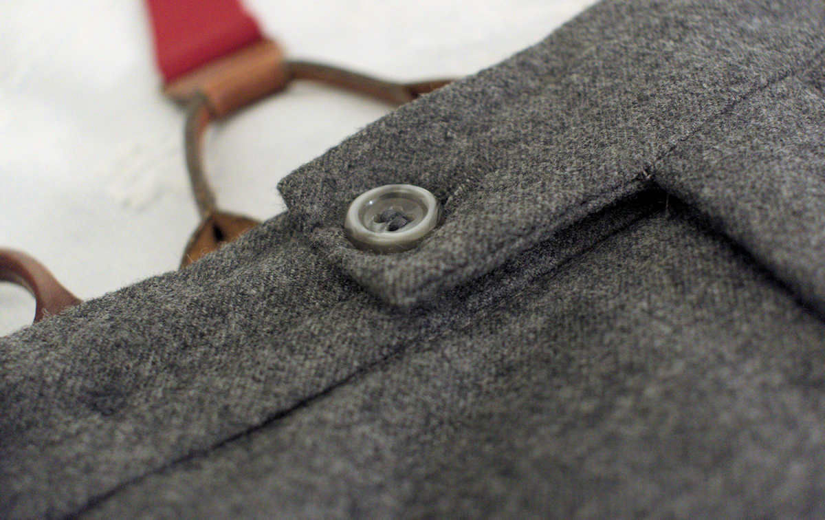 Φανελένιο γκρι παντελόνι με μικρή προεξοχή στο ζωνάρι και κουμπιά για τιράντες, ραμμένο από τον Γιώργο Κωβαίο